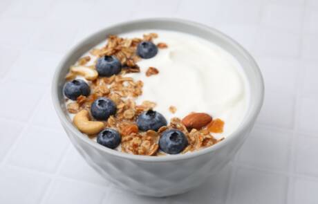 Bowl,With,Yogurt,,Blueberries,And,Granola,On,White,Tiled,Table,