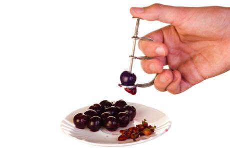 Cherry,Pitter,In,Hand,And,Cherries,On,Plate